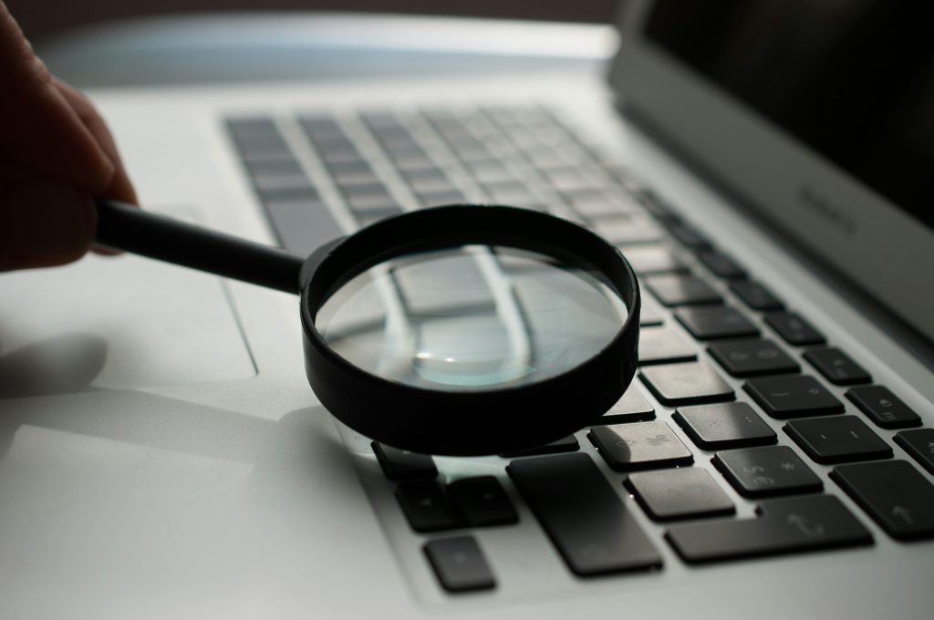A magnifying glass laying on top of a laptop keyboard.