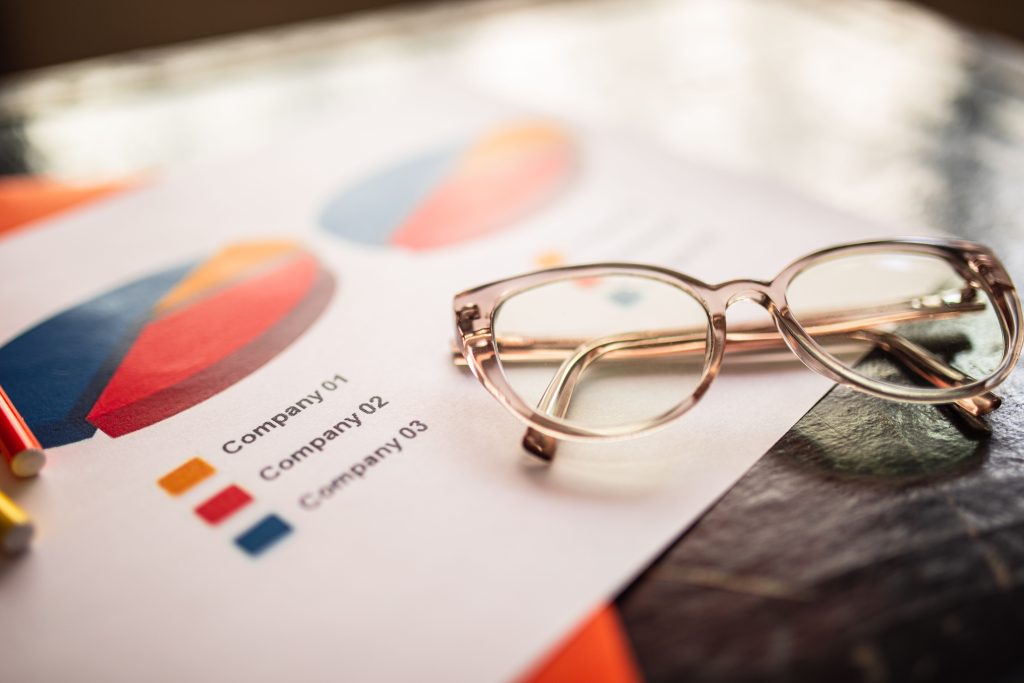 A pair of glasses sitting on top of pie charts comparing several SEO companies.
